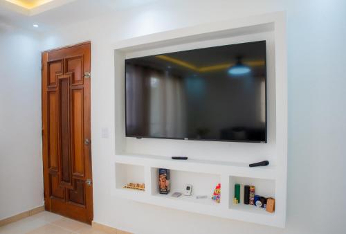 een flatscreen-tv aan een muur in een kamer bij Luxury, cozy apartment Alma Rosa /15 min airport in Los Tres Ojos de Agua