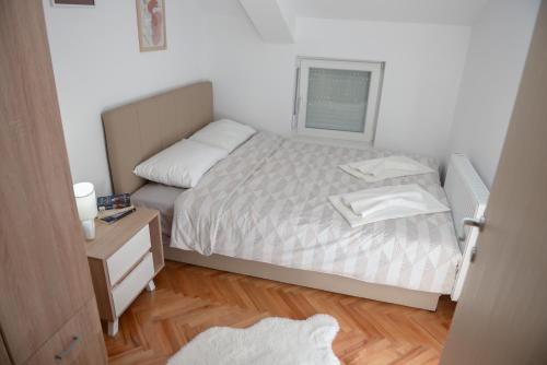 a small bedroom with a bed and a wooden floor at MD apartman Vranje FREE PARKING in Vranje