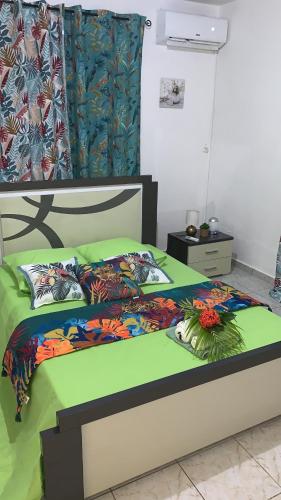 ein Bett mit bunter Bettdecke und Blumen darauf in der Unterkunft villa des aigles in Anse-Bertrand