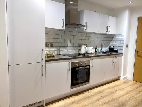 een keuken met witte kasten en een fornuis met oven bij Elegant & Cozy, Gold Decor Apartment, B1 in Birmingham