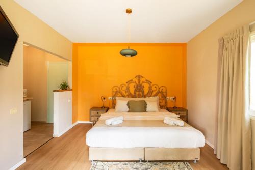 a bedroom with a bed with an orange wall at Mantur West Galilee by Selina in Loẖame HaGetaʼot