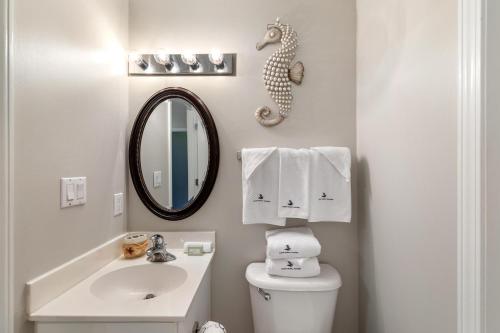a bathroom with a sink and a toilet and a mirror at Windemere 904 Pool Side Cabana Included! in Perdido Key
