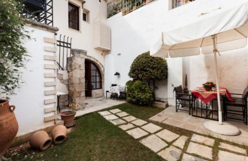 a patio with a table and an umbrella in a yard at Calergi Residence - Holidays in Crete in Atsipopoulo
