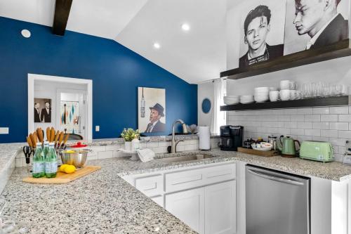 a kitchen with white cabinets and blue walls at The Sinatra in Bentonville
