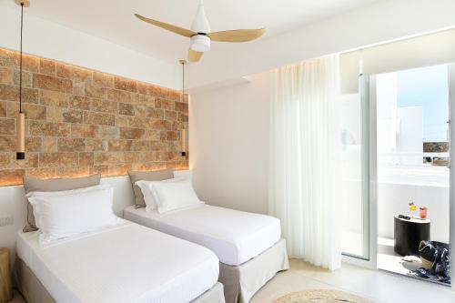 two beds in a room with a brick wall at Ios Art Suites in Ios Chora
