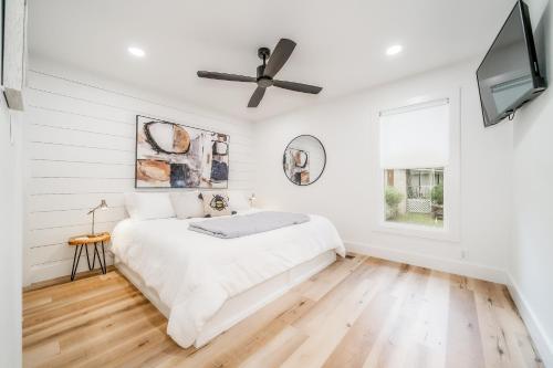 a white bedroom with a bed and a ceiling fan at The Beehive in Lake Hamilton