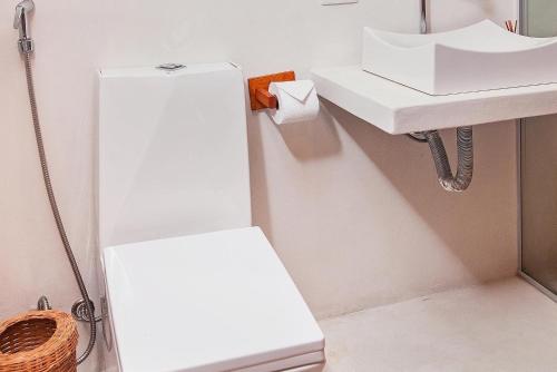 a white bathroom with a sink and a toilet at Mirante Caraiva in Caraíva
