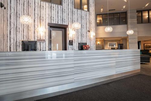 a lobby with a large white counter in a building at Sandman Signature Edmonton South Hotel in Edmonton