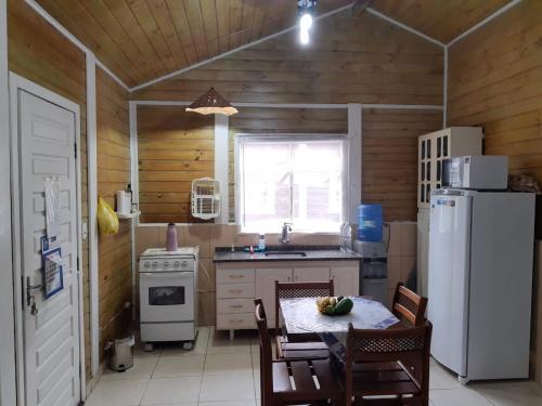 eine Küche mit einem Tisch und einem weißen Kühlschrank in der Unterkunft Casa Condomínio Boiçucanga in Boicucanga