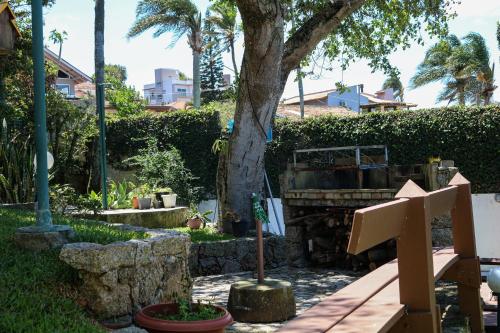 a garden with a tree and a wooden bench at Hostel Jardim das Bruxas 410 in Florianópolis