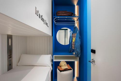a small bedroom with a bed and a blue wall at COEO Pod Hostel - Part of COEO Experience in Málaga
