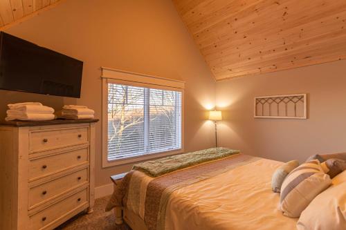 a bedroom with a bed and a dresser and a window at The Grape Escape at Eagles Nest in Elk Park