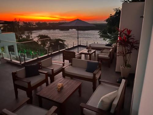 a balcony with couches and tables and a sunset at Suítes Luxo Marambaia- Epic House in Rio de Janeiro