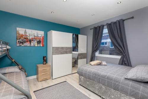 a bedroom with blue walls and a bed and a mirror at Central Roof Terrace Apartment in Stockton-on-Tees