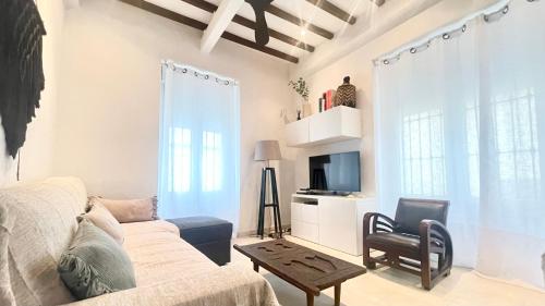 ein Wohnzimmer mit einem Sofa, einem Tisch und einem TV in der Unterkunft TarifaMiCasa Santa Barbara in Tarifa