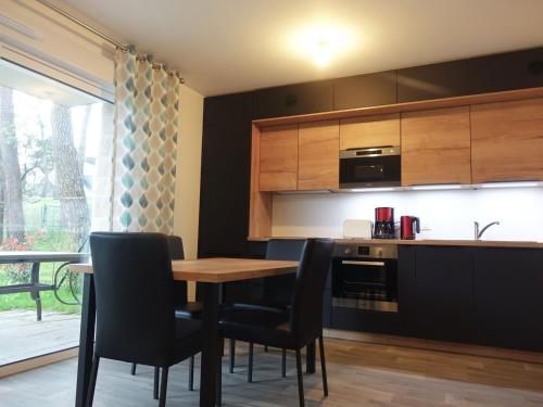 une cuisine avec une table en bois et des chaises noires dans l'établissement Appartement neuf 2-4 pers, terrasse et jardin, à 400m de la plage du Rohaliguen - FR-1-639-35, à Sarzeau