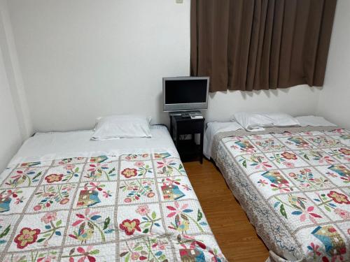 Duas camas num quarto com televisão em Marunishi em Osaka