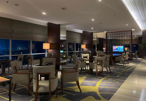 a hotel lobby with tables and chairs and a television at Crowne Plaza Bandung by IHG in Bandung