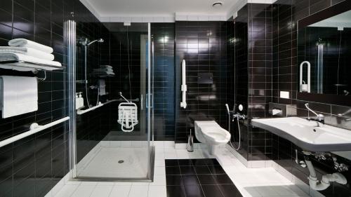 La salle de bains est pourvue de carrelage noir, d'un lavabo et de toilettes. dans l'établissement Holiday Inn Nola - Naples Vulcano Buono, an IHG Hotel, à Nola