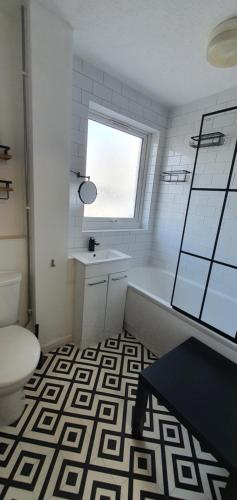 a bathroom with a tub and a toilet and a window at Glenfield Park House in Leicester