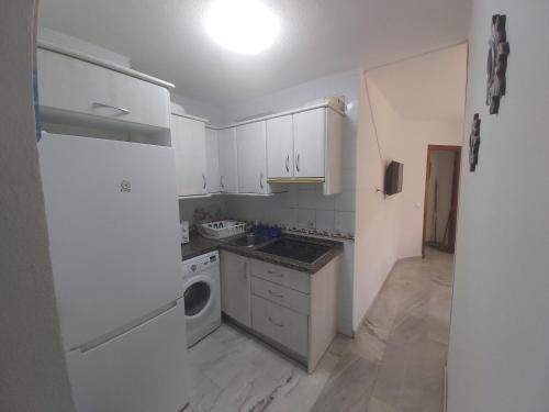 a kitchen with white cabinets and a white refrigerator at Apartamento Sostoa 4 in Málaga