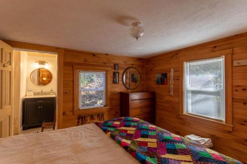 a bedroom with wooden walls and a bed and a sink at Hidden Cabin on Old Field Creek in Fleetwood