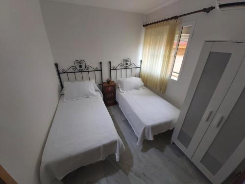 two beds in a small room with a window at Apartamento Sostoa 4 in Málaga