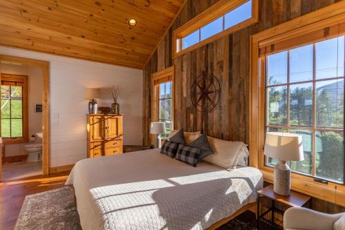 a bedroom with wooden walls and a bed and windows at Banner Sky in Banner Elk