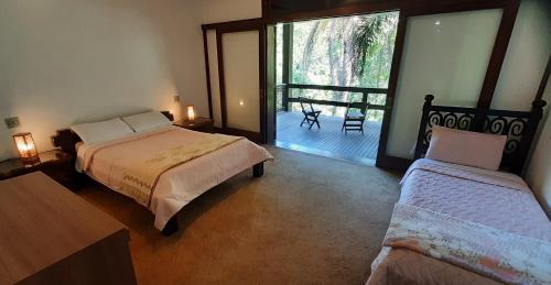 a bedroom with two beds and a balcony at Canto das Águas Atibaia in Atibaia