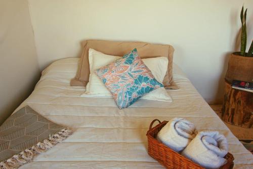 a bed with a basket of towels and a pillow at Casa Mostaza-Ecolodge in Samaná