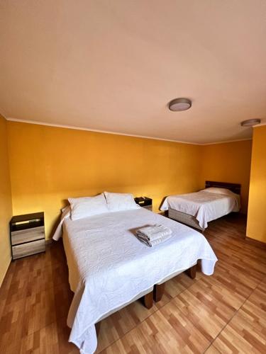 a bedroom with two beds and a yellow wall at HOSTAL APANANTOR 1 in San Pedro de Atacama
