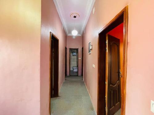 a hallway with pink walls and two doors and a hallway with a hallway at Charmante maison cozy et conviviale in Bafoussam