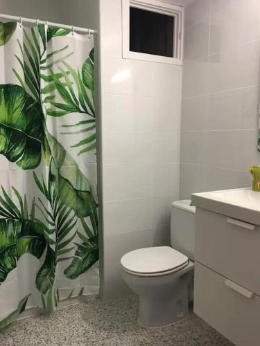 a bathroom with a toilet and a green leaf shower curtain at Casa Jesùs in Ontinyent