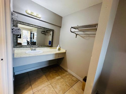 a bathroom with a sink and a mirror at Casa Blanca Express & Suites Cypress Buena Park - Anaheim Area in Cypress