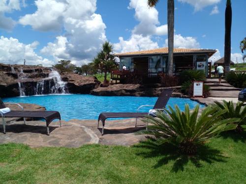 - une piscine avec une cascade et 2 chaises en face d'une maison dans l'établissement Chalezinho Pousada, à Brumadinho