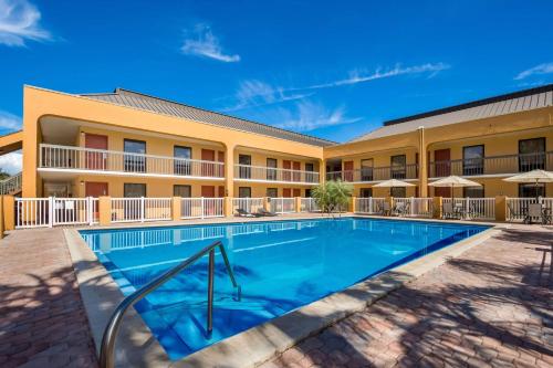 a pool in front of a hotel with tables and umbrellas at SureStay Hotel by Best Western St Pete Clearwater Airport in Clearwater