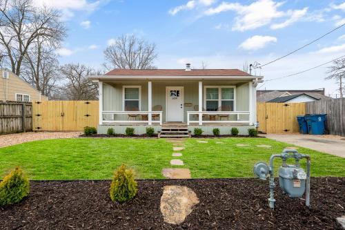a white house with a fence and a yard at B Street Bungalow in Bentonville
