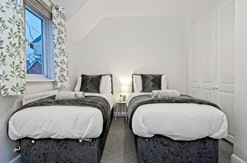 two twin beds in a room with a window at StayRight 2 Bed Beach House with Private Parking- Next to Barry Beach and Jackson Bay in Barry