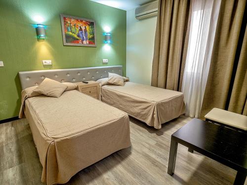 a hotel room with two beds and a table at Hostal Real Aranjuez in Aranjuez