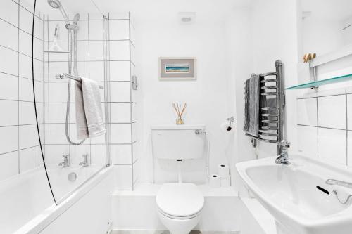 a white bathroom with a toilet and a sink at Curlew Cottage - Character Cottage with Superb River Views in Dittisham