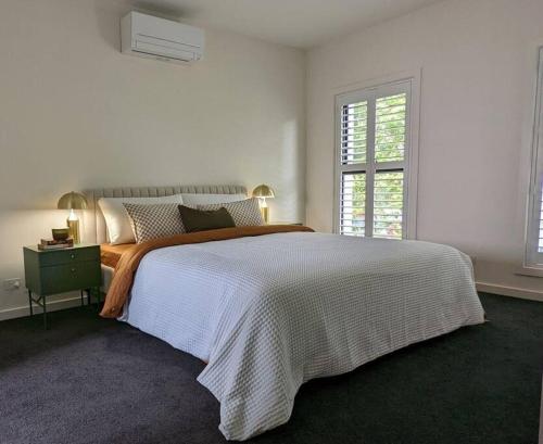 a white bedroom with a large bed and a window at Location & luxury 2BR 2 Bath in Albury