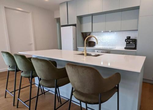 a kitchen with a counter with a sink and chairs at Location & luxury 2BR 2 Bath in Albury