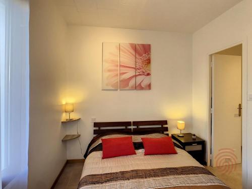 une chambre avec un lit avec deux oreillers rouges dans l'établissement Charmant F2 avec Wifi à 150m des Thermes et centre-ville de Lamalou-les-Bains - FR-1-451-149, à Lamalou-les-Bains