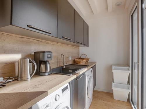 a kitchen with a sink and a washer and dryer at Maison 3 étoiles, piscine chauffée, accès plage privée, 12 couchages, proche lac et forêt - FR-1-521-185 in Biscarrosse
