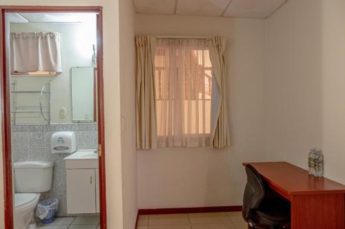 a bathroom with a toilet and a sink and a window at Hotel Windsor Plaza in San Salvador