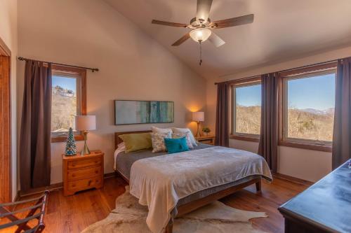 Schlafzimmer mit einem Bett, einem Deckenventilator und Fenstern in der Unterkunft Escape to Blue Ridge in Blowing Rock