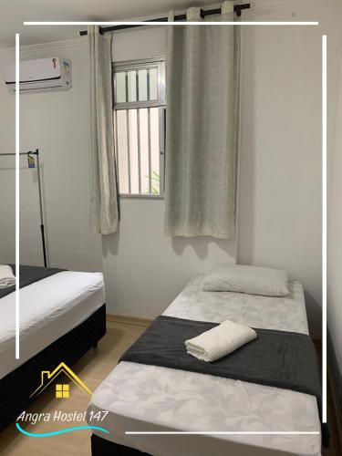 um quarto com 2 camas e uma janela em Angra Hostel 147 em Angra dos Reis