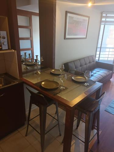 a dining room table with four chairs and a couch at Acogedor y renovado Departamento in Santiago