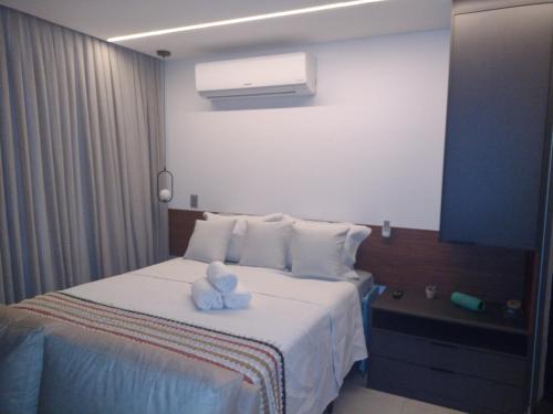 un osito de peluche sentado en una cama en una habitación de hotel en Box 150 Joia Rara no Caribessa, en João Pessoa