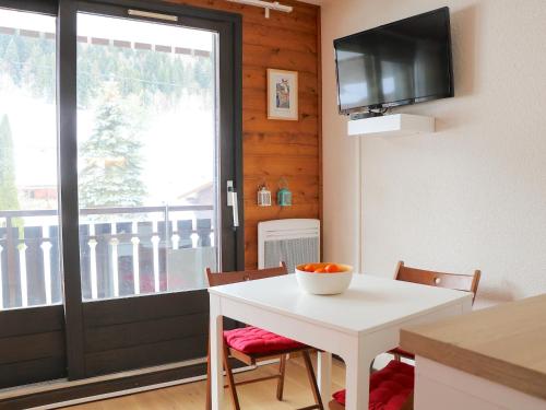 une salle à manger avec une table blanche et une télévision dans l'établissement Studio cosy entre pistes et sentiers – Parking inclus - FR-1-498-71, à Bernex